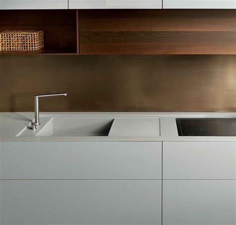 A Modern Kitchen With White Cabinets And Stainless Steel Faucets