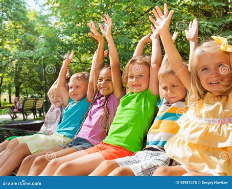 Happy Cheering Kids Lifting Hands On The Bench Stock Image