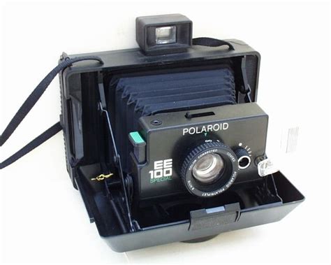 An Old Polaroid Camera Sitting On Top Of A Black Box With A Strap Around It
