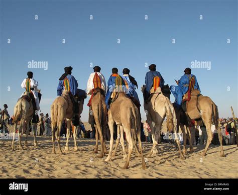 Tuareg Men On Camels Dressed In Traditional Robes Arriving At The