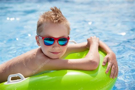 Little Boy Swimming In The Pool With Big Bright Green Rubber Ring