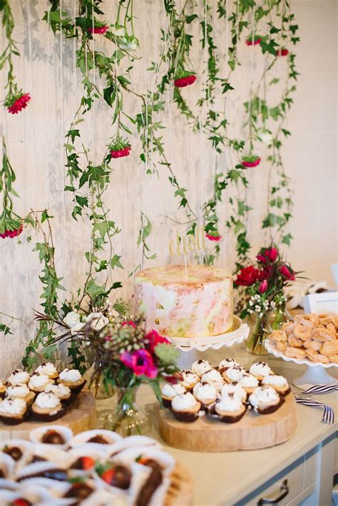 An Assortment Of Desserts And Pastries On A Table In Front Of A Floral Wall