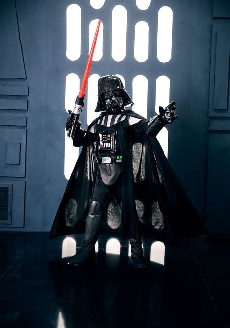 A Darth Vader Standing In Front Of A Window With His Lights On And Arms Out
