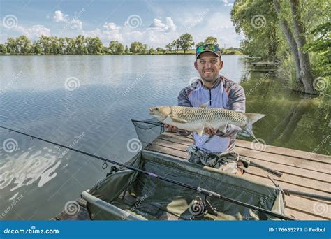 Amur Fishing Fisherman With Grass Carp Fish In Hands At Lake Stock
