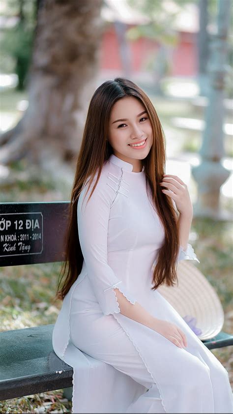 a woman sitting on top of a wooden bench next to a tree and grass covered ground