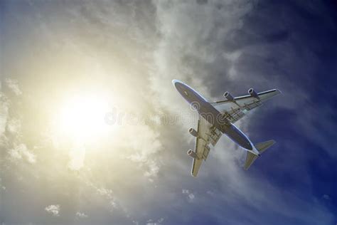 Commercial Airplane Flying Above Clouds In Dramatic Sunset Light Stock