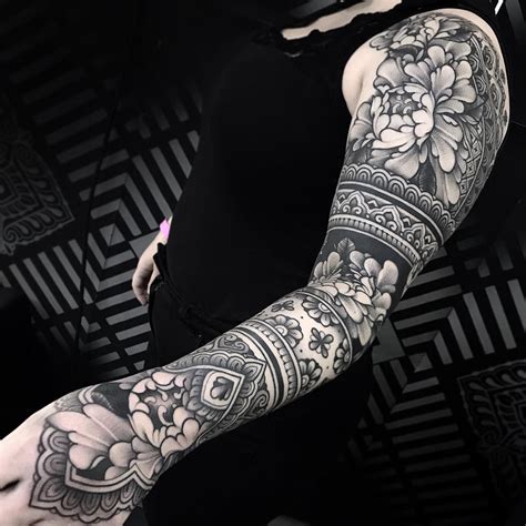 A Woman With Tattoos On Her Arms And Arm Sleeve Is Holding A Cell Phone