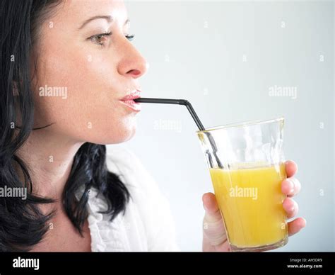 Woman Drinking Large Glass Of Fresh Orange Juice Through Straw Stock