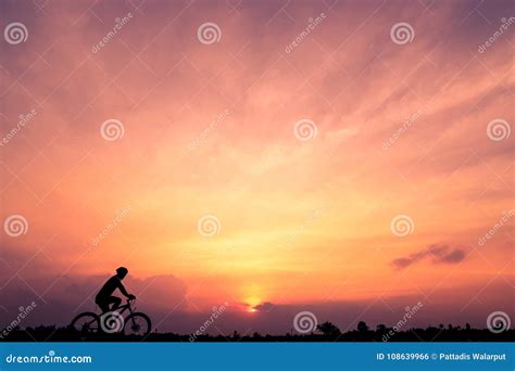 Silhouette Of Cyclist Ride Bicycle On Sunset Background Stock Photo