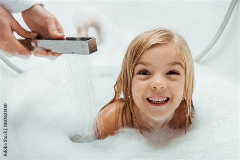 Cute And Naked Kid Taking Bath Near Mother In Bathroom Stock Photo
