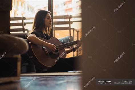 Woman Playing Guitar While Sitting On Floor At Home Art People