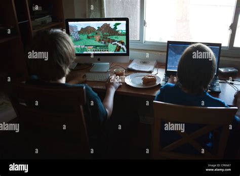 Two Boys Playing The Video Game Minecraft At Home On Computers Stock
