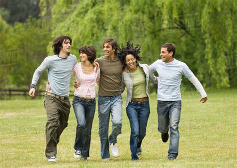 Group Of Young Friends With Arms Around Each Other Skipping Across
