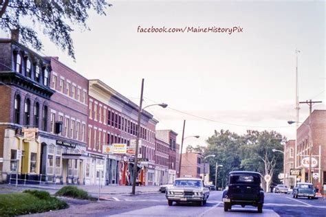 An Old Car Is Driving Down The Street In Front Of Some Buildings And