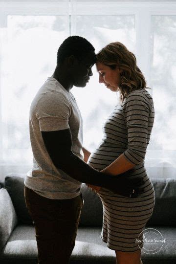 A Pregnant Couple Standing In Front Of A Window