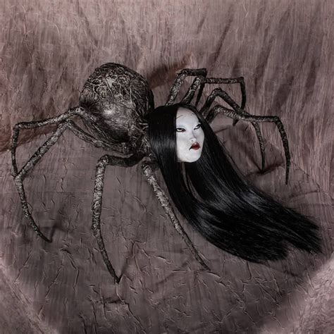 A Woman With Long Black Hair Sitting Next To A Spider On Top Of A Bed