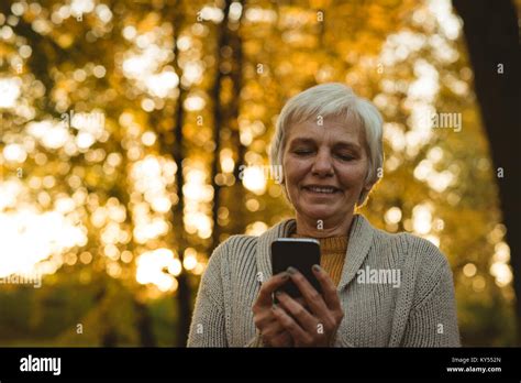 Smiling Senior Woman Using A Smart Phone In A Park Stock Photo Alamy