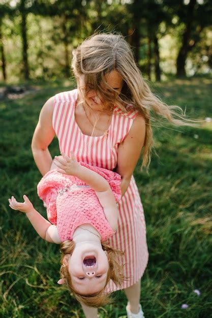 Premium Photo Happy Mother Spins The Daughter On Hands On Nature On