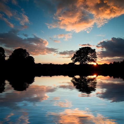 Stunning Sunset Silhouette Reflected In Calm Lake Water Photograph By