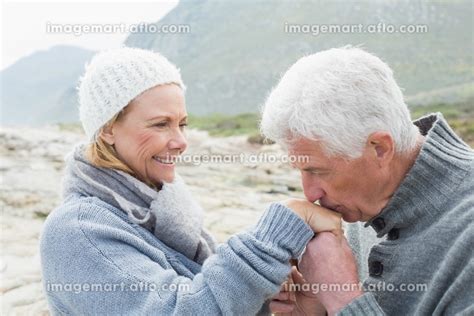 Side View Of A Senior Man Kissing Happy Womans Hand At The Rocky Beach