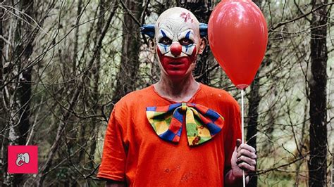 A Man In Clown Makeup Holding A Red Balloon