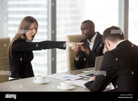 Angry Female Furious Boss Scolding Employee At Mixed Race Team Meeting