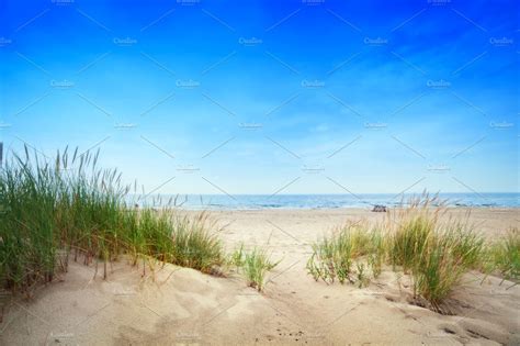 Beach With Dunes And Green Grass Containing Beach Sand And Ocean