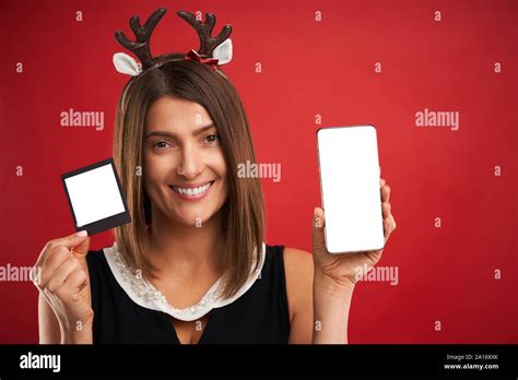 Woman In Christmas Mood Comparing Instant Pictures To Smartphone Camera