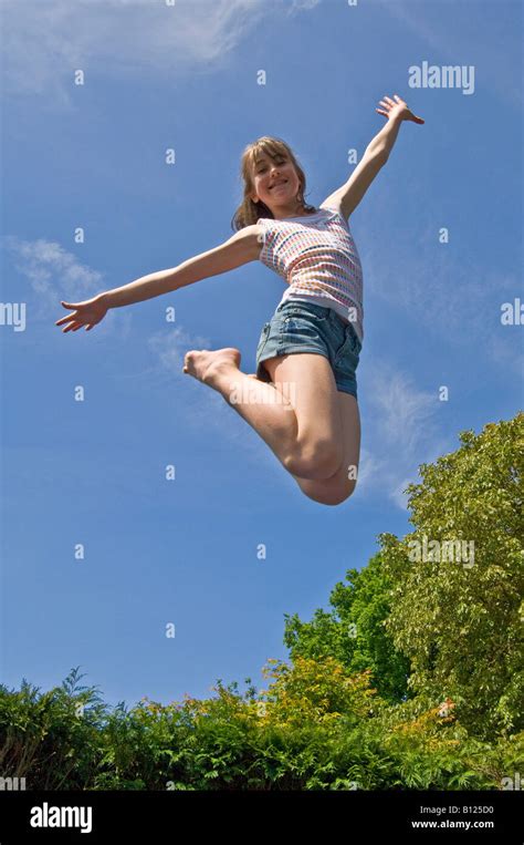A Young Girl 10 Yrs Jumping From A Trampoline In Mid Air On A Bright