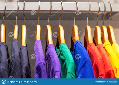 Bright Multicolored T Shirts Hang On Wooden Hangers In The Store Stock