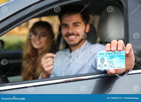 Young Man Holding Driving License In Car With Passenger Stock Image