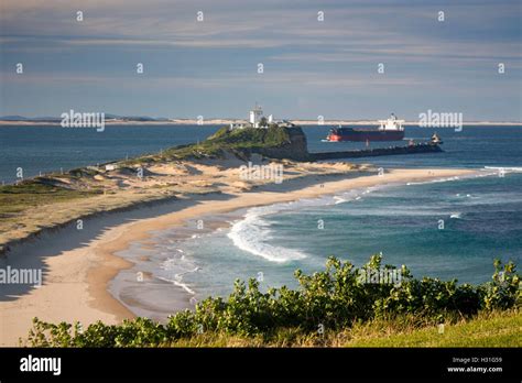Nobbys Beach And Lighthouse With Ship Being Guided By Tugs Through