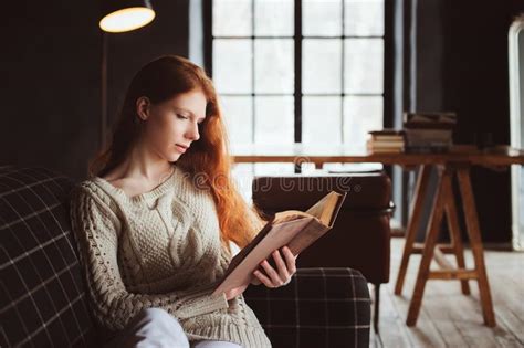 Young Beautiful Redhead Woman Relaxing At Home In The Autumn Cozy Evening And Reading Book Stock