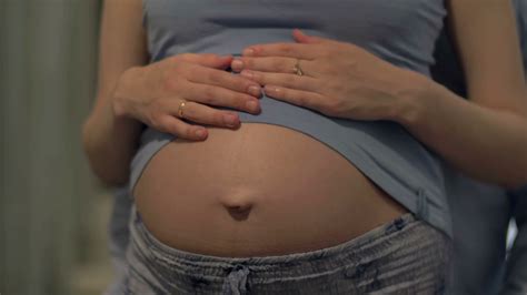 Close Up Shot Of Pregnant Woman Smoothing The Bare Belly And Future Father Holding Gently His