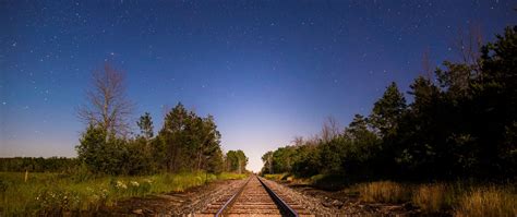 Download Wallpaper 2560x1080 Railway Starry Sky Direction Trees Dual