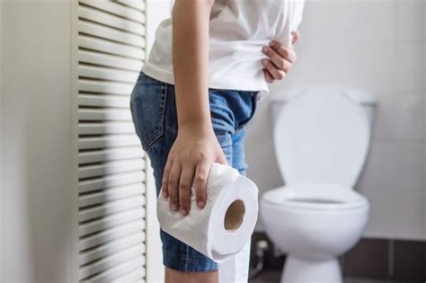 Die verbesserte und ergänzte 5. Asiatischer junge, der auf der toilettenschüssel hält seidenpapier - gesundheitsproblemkonzept ...