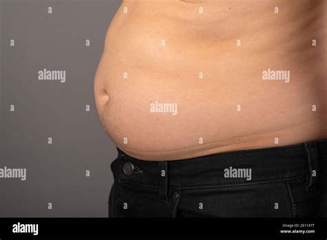 Close Up Picture Of Young Mans Bloated Stomach In Front Of Grey