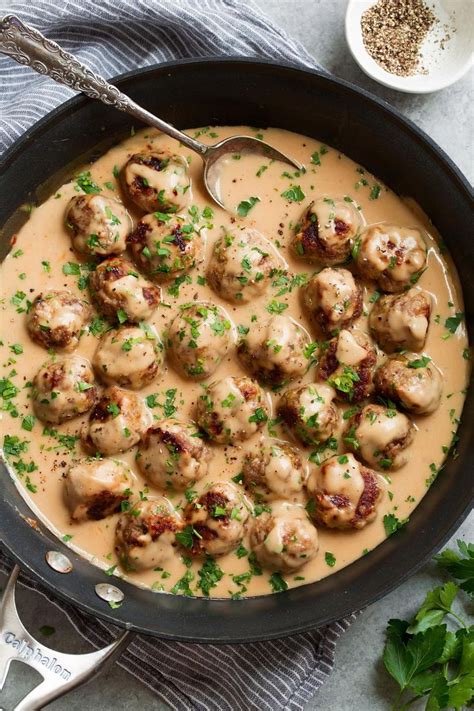 A Skillet Filled With Meatballs Covered In Gravy And Garnished With Parsley