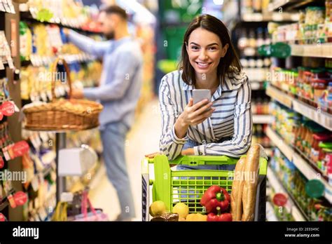 Young Woman With Mobile Phone Shopping In Hypermarket Stock Photo Alamy
