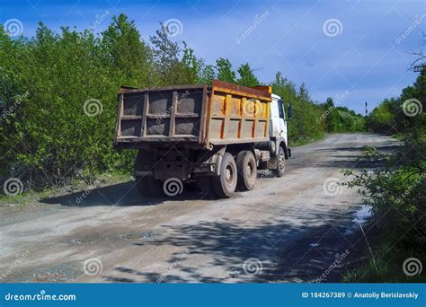 Lorry Dump Truck Rides On A Dirt Road Against The Background Of The