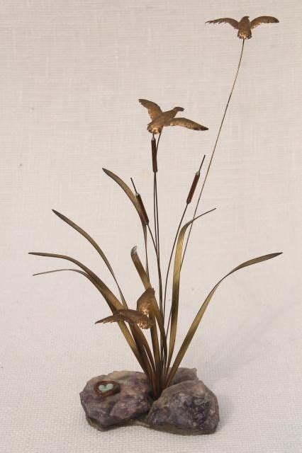 Two Birds Are Flying Over Some Plants In A Rock And Gravel Vase On A