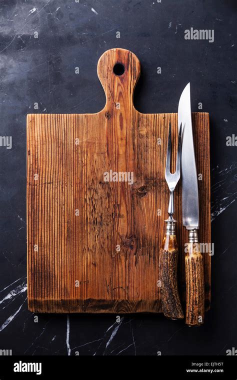 Tabla de cortar y picar tenedor y cuchillo tallado en mármol oscuro fondo Fotografía de stock