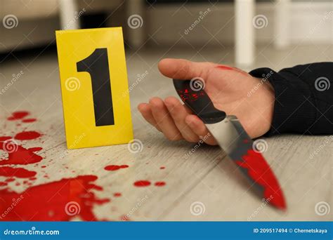 Crime Scene Marker And Dead Body With Bloody Knife On Floor Closeup