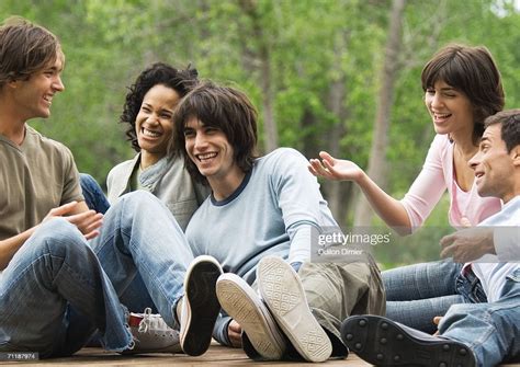 Group Of Young Friends Sitting Around Together Outdoors Laughing Stock