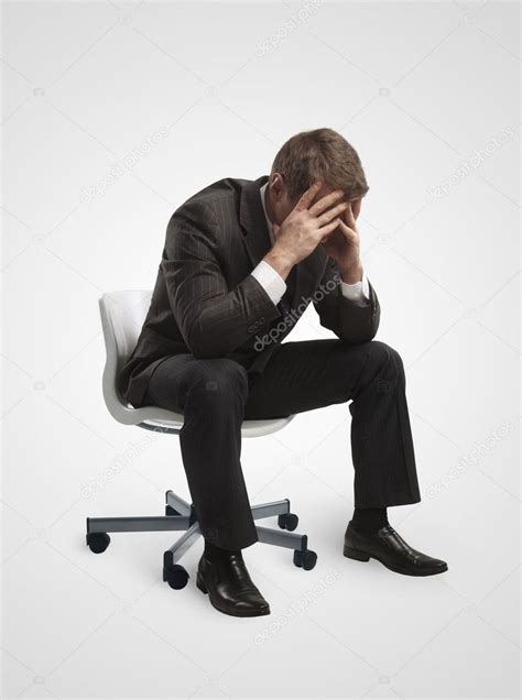 Young Businessman Sitting On Chair With Head Down As If Sad Or