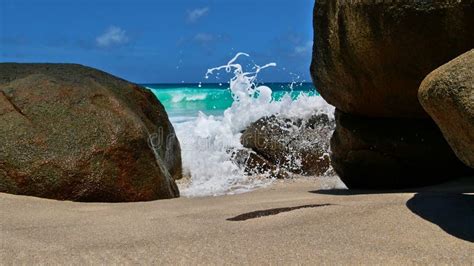 Waves Spilling Over Granite Rocks With Spray On Tropical Beach Anse