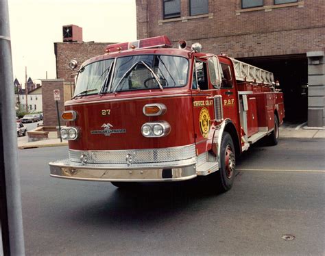 a red fire truck driving down a street next to a tall brick building