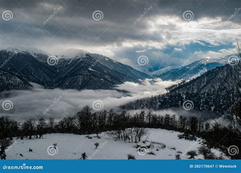 Picturesque Landscape With Snow Capped Mountaintops And A Few Wispy