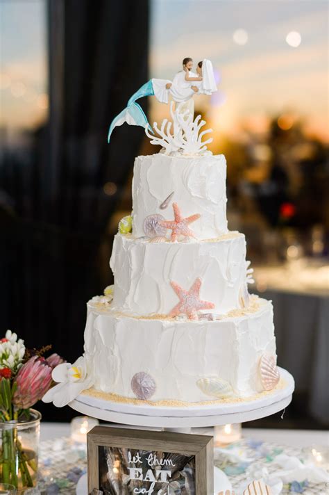 Wedding arch decorated on caribbean beach. Beach-Themed Wedding Cake With Mermaid Cake Topper