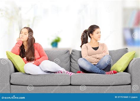 Two Angry Teenage Girls Sitting On Sofa At Home Stock Photo Image